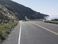 the highway is running right next to the big mountains and the ocean in the background