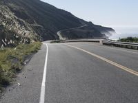 the highway is running right next to the big mountains and the ocean in the background