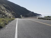 the highway is running right next to the big mountains and the ocean in the background