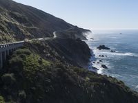 the train rides on the track over the cliff near the ocean and cliffs with sea and mountains in the distance