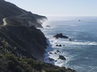 the train rides on the track over the cliff near the ocean and cliffs with sea and mountains in the distance