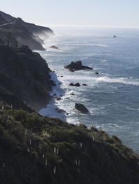 the train rides on the track over the cliff near the ocean and cliffs with sea and mountains in the distance