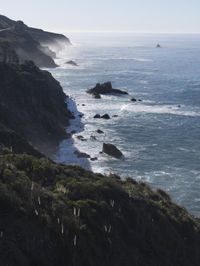 the train rides on the track over the cliff near the ocean and cliffs with sea and mountains in the distance