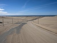 a paved beach with a fence in front of it and the ocean in the distance