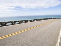 a man riding his motorcycle on a road next to the water with an ocean in the background