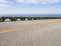 a man riding his motorcycle on a road next to the water with an ocean in the background