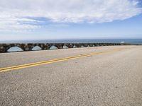 a man riding his motorcycle on a road next to the water with an ocean in the background