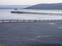 there are many cars going down the road to the beach and pier in the background