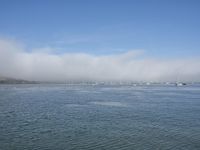 large body of water with lots of boats floating in it on a hazy day with blue skies