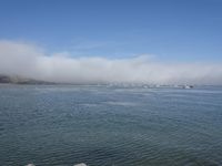 large body of water with lots of boats floating in it on a hazy day with blue skies