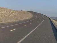 the curved road on a hillside is empty except for traffic to pass by and get to