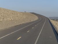 the curved road on a hillside is empty except for traffic to pass by and get to