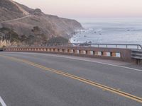 an open road that leads to a beach and a body of water on the other side of it