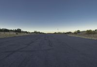 the road in the middle of the field is empty and paved and empty, with a clear blue sky
