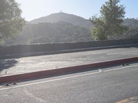 the two skateboarders ride down the road under a clear sky with mountains in the distance