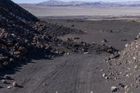 several rocks are scattered near a rocky area on the edge of a valley with many mountains in the distance