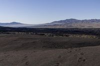 a lone, deserted mountain range in the background as it stands near an area that has been burned by lava