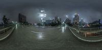 a view of city from across the street on a cloudy day at night as seen through a spherical fisheye lens