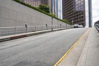 a street with concrete walls is lined with railings and cars are parked along the road