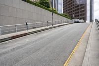 a street with concrete walls is lined with railings and cars are parked along the road