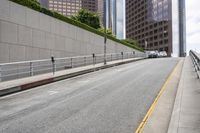 a street with concrete walls is lined with railings and cars are parked along the road