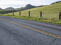 a highway is lined by two yellow double line lines while mountains stand in the distance