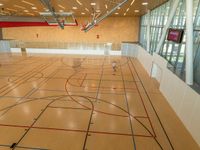 an indoor gymnasium with basketball court and lighting beams and lots of windows with a sign on the wall