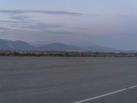 an airport has some mountains in the background on the airfield runway in the foreground