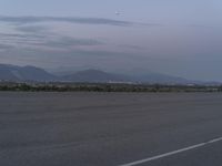 an airport has some mountains in the background on the airfield runway in the foreground