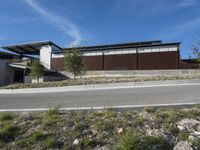 a residential house is sitting on a hill side in the middle of the desert with a lot of rocks and grass to the left