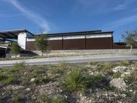 a residential house is sitting on a hill side in the middle of the desert with a lot of rocks and grass to the left