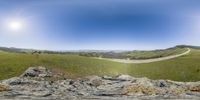 the fisheye lens view shows an empty road running through a mountain valley with hills