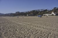 a group of people on a beach next to the ocean and a resort on the horizon