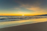 a beautiful ocean beach with bright orange and yellow skies at sunset, which is reflected in the sand