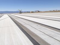 an airplane runway with lines going down the side of it, with mountains in the distance