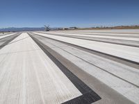 an airplane runway with lines going down the side of it, with mountains in the distance