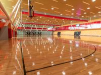 the gymnasium of a college sports complex with a basketball court and an indoor gym, with hardwood and steel floors