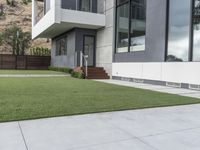 the concrete ground of a modern home is clean, with the green lawn in front and the walkway below