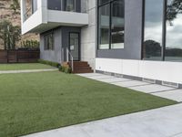 the concrete ground of a modern home is clean, with the green lawn in front and the walkway below