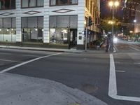 an empty street with people walking and a traffic light at night, on an otherwise quiet street corner