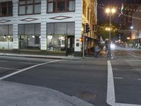 an empty street with people walking and a traffic light at night, on an otherwise quiet street corner