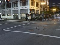 an empty street with people walking and a traffic light at night, on an otherwise quiet street corner