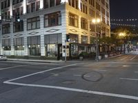 an empty street with people walking and a traffic light at night, on an otherwise quiet street corner