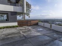 the concrete patio is surrounded by cement tiles with steel posts, a wooden privacy fence and greenery