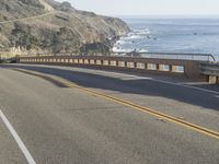 a truck is going down the road near the ocean and cliffs in the distance, which are two rows