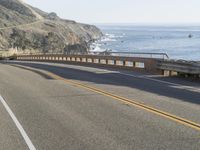 a truck is going down the road near the ocean and cliffs in the distance, which are two rows