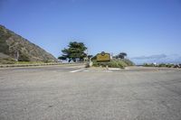 an empty road and parking lots with the view of the ocean on the horizon in the background