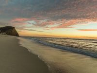 a sunset view from the beach with clouds above it and the water and the sand along the shore