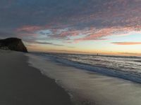 a sunset view from the beach with clouds above it and the water and the sand along the shore
