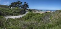 a scenic road with the beach in the distance and the ocean in the background behind it